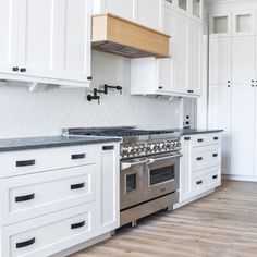 a kitchen with white cabinets and stainless steel stove top oven in the middle of it