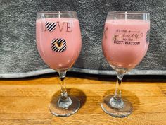 two glasses filled with pink liquid sitting on top of a wooden table next to each other