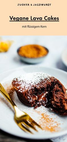 a white plate topped with chocolate cake next to a fork and bowl filled with powdered sugar