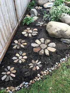 a garden with rocks and grass next to a fence