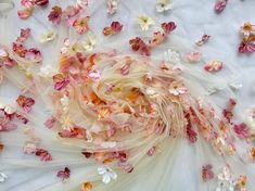 pink and white flowers are scattered on the ground next to sheer fabric, which has been draped over it