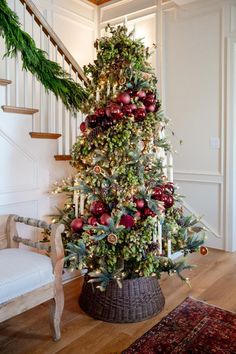 a decorated christmas tree in the corner of a room with stairs leading up to it