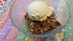 a glass bowl filled with ice cream on top of a colorful tablecloth covered table