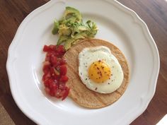 an egg is on top of a tortilla with tomatoes and avocado