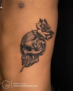 a woman's stomach with a skull and rose tattoo on it