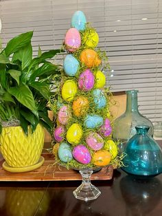 an arrangement of easter eggs and plants on a table