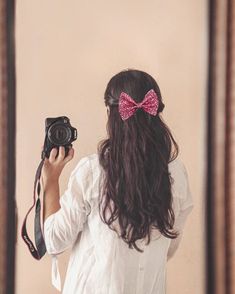 a woman taking a selfie in front of a mirror with a camera on her shoulder