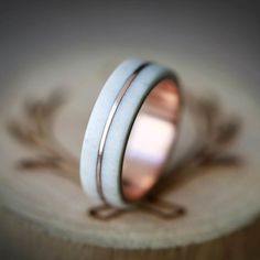 two wedding bands are sitting on top of a wooden piece