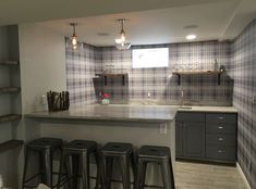 a kitchen with four stools and a bar in the middle, next to some shelves