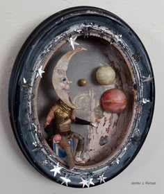 a clock with an image of the moon, planets and man sitting on it's side