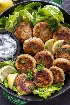 crab cakes in a bowl with lettuce and lemon wedges