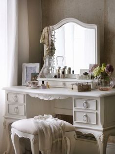 a white dressing table with a mirror and stool