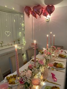 a long table is set with many plates and candles for valentine's day dinner