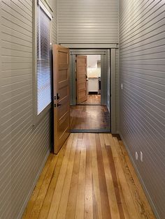 an open door leading into a room with wood floors and white siding on the walls