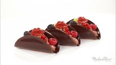 four pieces of chocolate with berries and raspberries on top