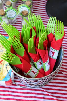 green forks and red napkins in a bucket on a striped tablecloth with cupcakes