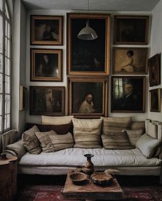 a living room filled with lots of paintings on the wall next to a white couch