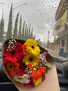 a bouquet of flowers sitting in the passenger seat of a car on a rainy day