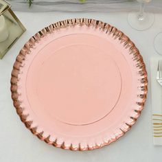 a pink plate sitting on top of a table next to silverware and napkins