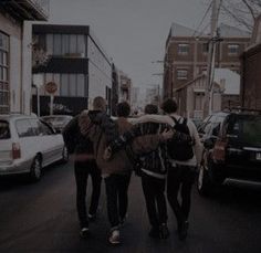 three young men walking down the street with their arms around each other