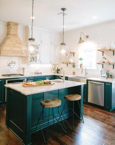 a kitchen with two stools in front of the island