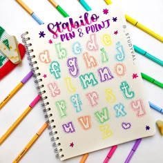 an open notebook with colorful crayons and writing on it next to colored pencils