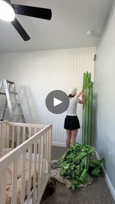 a woman standing next to a baby crib in a room with green vegetables on the floor