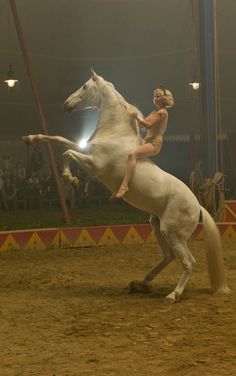 a woman riding on the back of a white horse