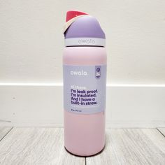 a pink and purple water bottle sitting on top of a white wooden floor next to a wall