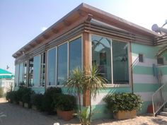 a green and white striped building with potted plants in front of it on the beach