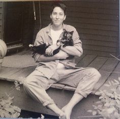 black and white photograph of a man sitting on a porch with a cat in his lap