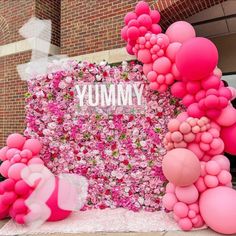 pink and white balloons are on display in front of a sign that says yummy