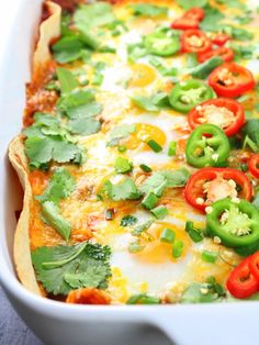 an enchilada dish with eggs, peppers and cilantro on top