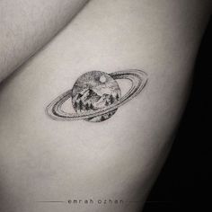 a small saturn tattoo on the back of a woman's left arm