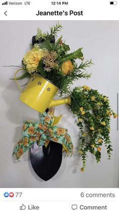 a yellow watering can is hanging on the wall next to a planter with flowers in it