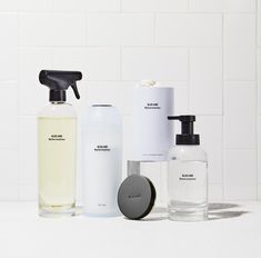 several different types of soaps and lotions on a white countertop in front of a tiled wall