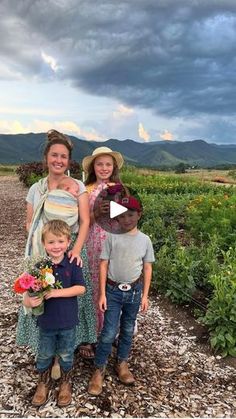 three children and an adult posing for a photo in front of a field with flowers