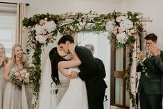 a bride and groom kissing in front of their wedding party at the end of the aisle