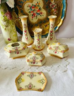 a table topped with vases and plates on top of a cloth covered tablecloth