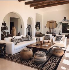 a living room filled with white furniture and lots of pillows on top of a rug