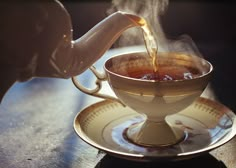 tea being poured into a cup on top of a saucer