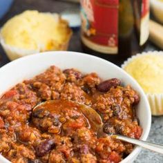 a white bowl filled with chili next to crackers