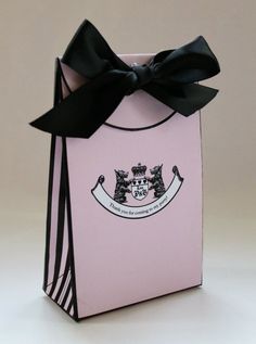 a pink gift bag with a black bow on the top and crest emblem on the front