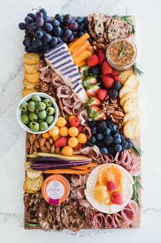 an assortment of cheeses, crackers and grapes on a platter with bread sticks