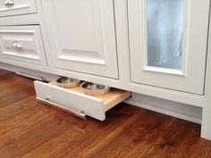 a kitchen with white cabinets and wooden flooring under the cabinet doors is shown in this image