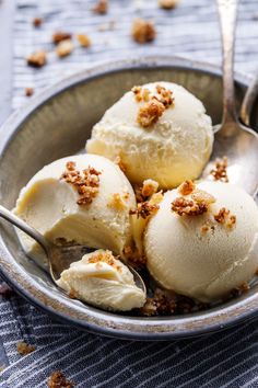 three scoops of vanilla ice cream in a bowl with spoon on the tablecloth