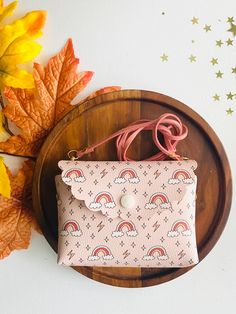 a pink purse sitting on top of a wooden tray next to autumn leaves and flowers