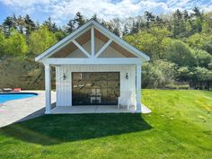 a white shed sitting on top of a lush green field next to a swimming pool