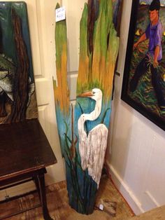 a painting of a white bird in the water next to two paintings on wooden boards