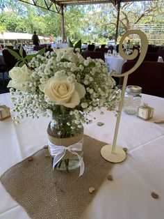 a vase filled with white flowers sitting on top of a table covered in burlocks